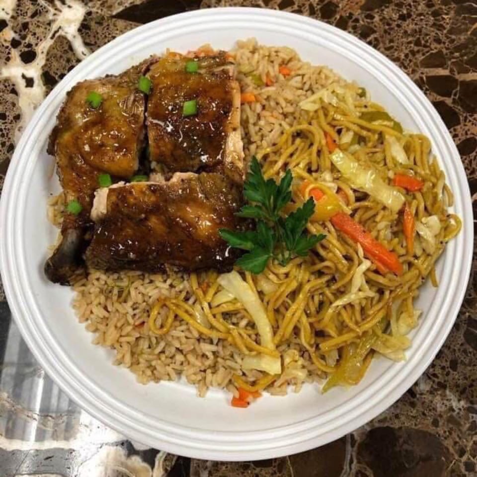 A white plate holds glazed chicken, fried rice, and lo mein noodles with vegetables.